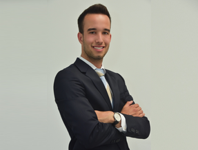 Ein Mann in einem Anzug steht selbstbewusst mit verschränkten Armen da.