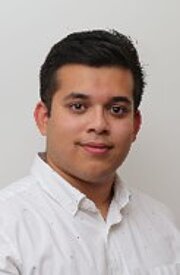 Ein Mann in einem weißen Hemd steht vor einer weißen Wand.